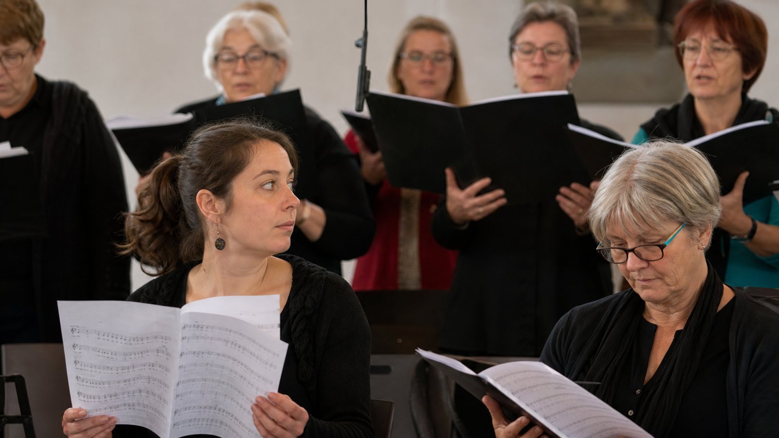 Chef de choeur accueillant une nouvelle choriste avant le début de la répétition