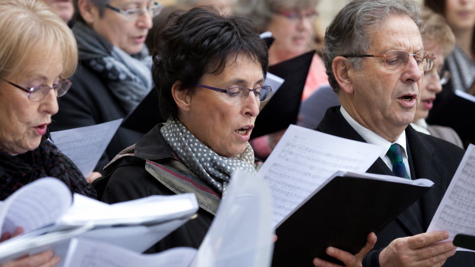 Choristes d'un même pupitre lisant leur partition pendant une répétition