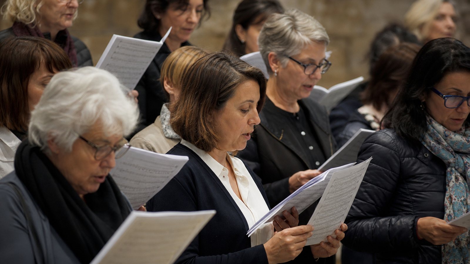 Choristes en répétition autour de leur chef dans une salle de musique