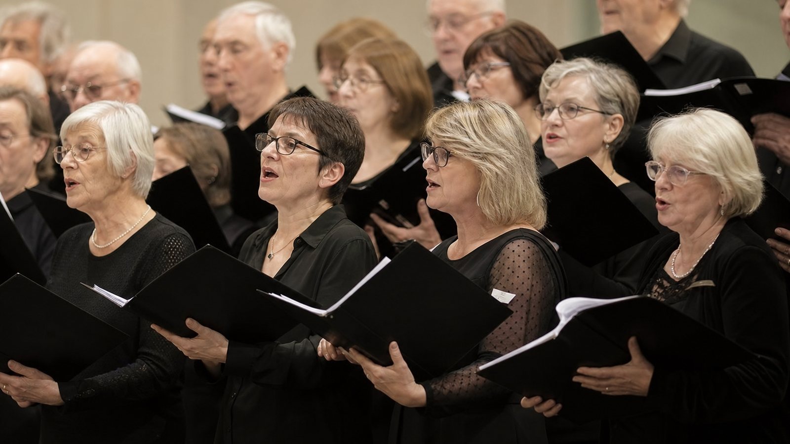 Chorale en concert sur scène devant le public, chef dirigeant les choristes